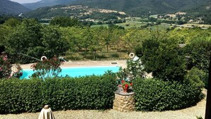 Une piscine entourée d’une végétation luxuriante, avec des collines en arrière-plan.