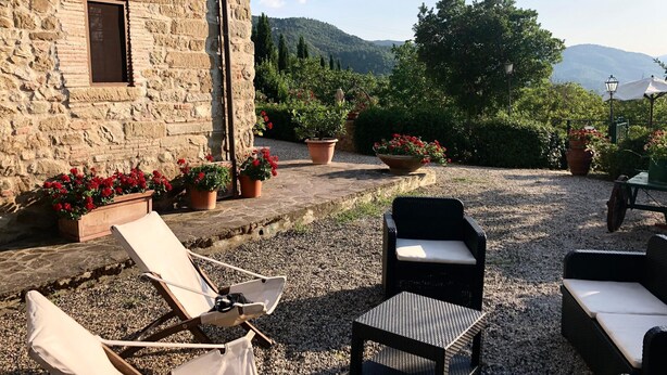 Un espace extérieur aménagé avec des murs en pierre, des plantes en pot et une vue sur la campagne.