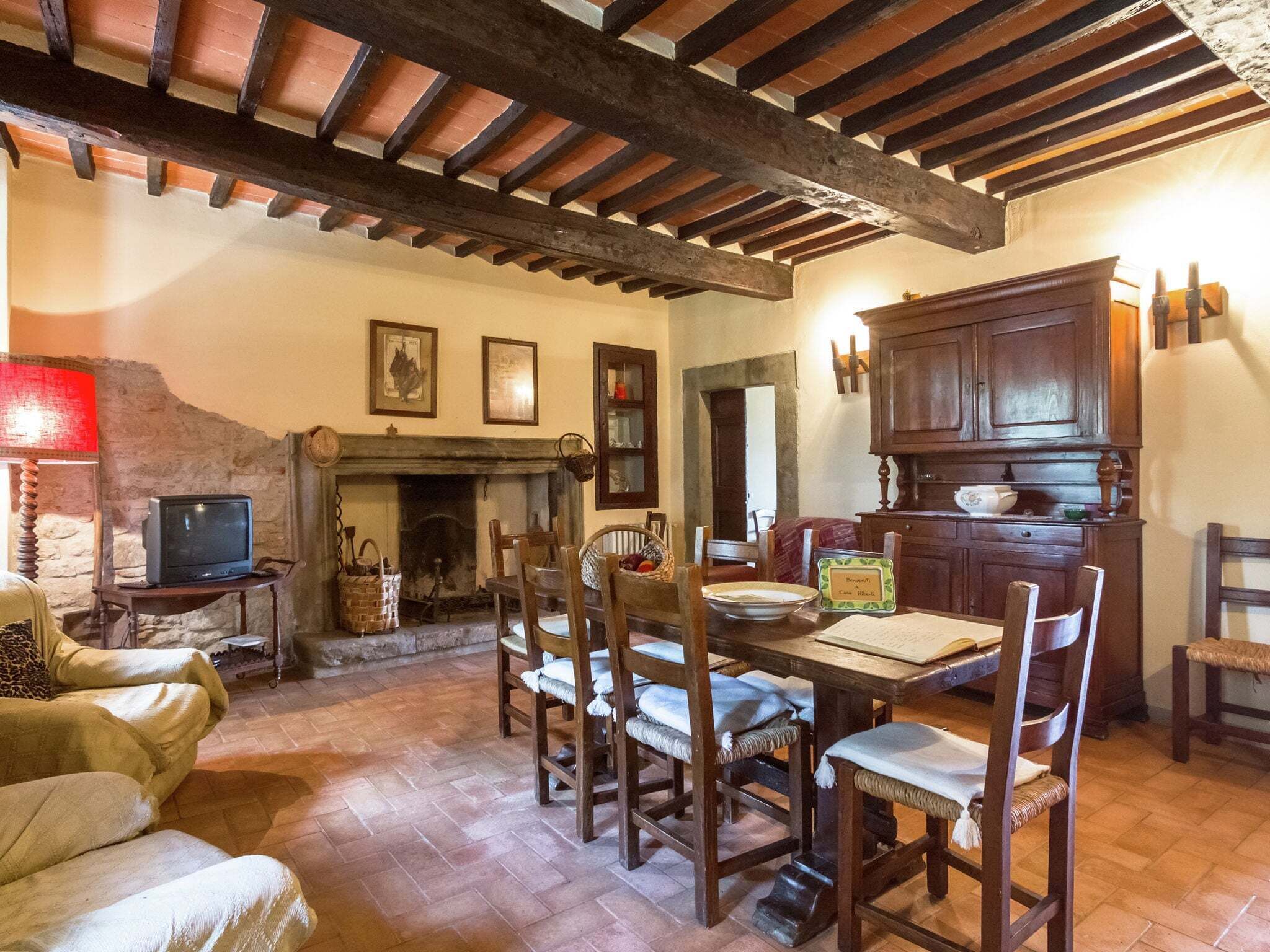 A rustic dining area with wooden furniture, a fireplace, and a television on a side table.