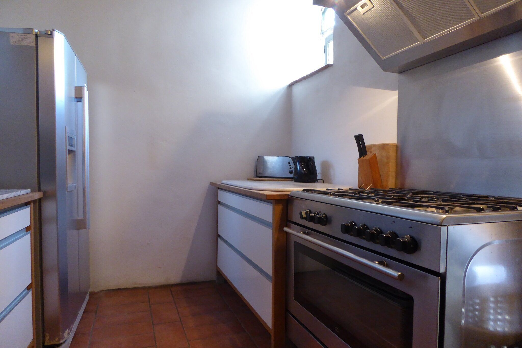 Une cuisine compacte équipée d’un réfrigérateur, d’un grille-pain, d’une cuisinière et d’un bloc à couteaux.