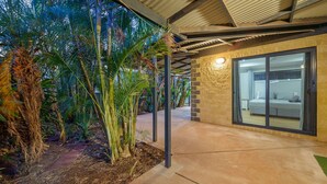 A modern hotel room with a large sliding glass door, a bed, and a view of the surrounding tropical garden. - 79 Nimitz Street - Pool and Pet Friendly (Exmouth)