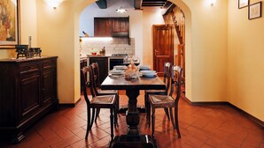 A dining area with a wooden table, chairs, and a kitchen in the background. - holiday home in Cortona (Cortona)