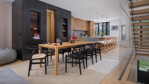 A modern kitchen with dark cabinetry, a wooden dining table, and a view of the outdoors.