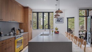 A modern kitchen with wooden cabinets, a central island, and a dining area with wooden chairs.