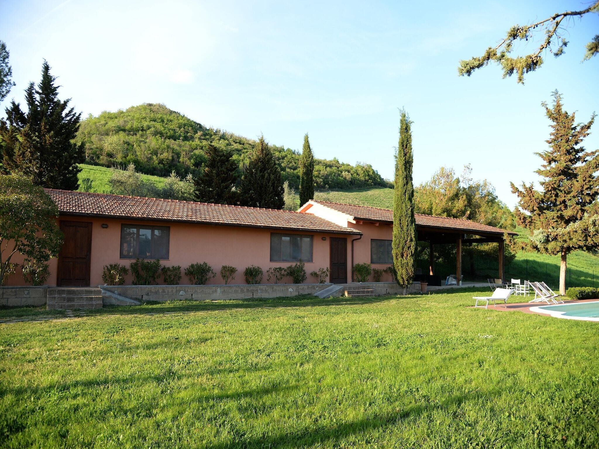 A two-story building with a tiled roof, a covered patio area, and a well-maintained lawn.