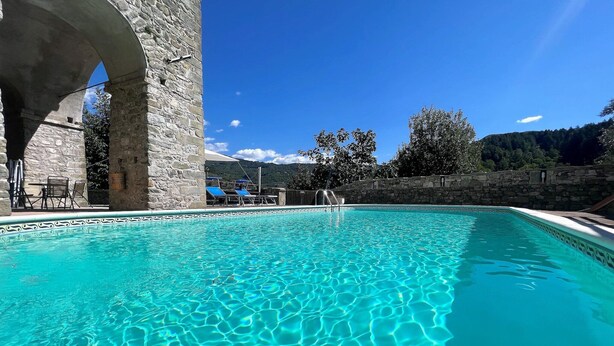 A clear blue pool with stone walls and a stone archway.