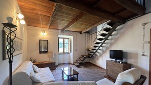 A cozy living room with a staircase, a sofa, a coffee table, and a television.