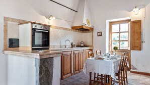 A kitchen with a stone island, wooden cabinets, and a dining area with a table set for four.