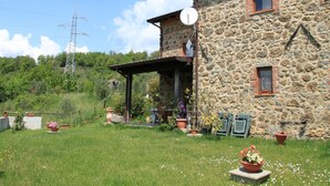 A stone building with a satellite dish, a covered outdoor area, and potted plants. - Holiday Home in Tuscany with Natural Pond (Mulazzo)