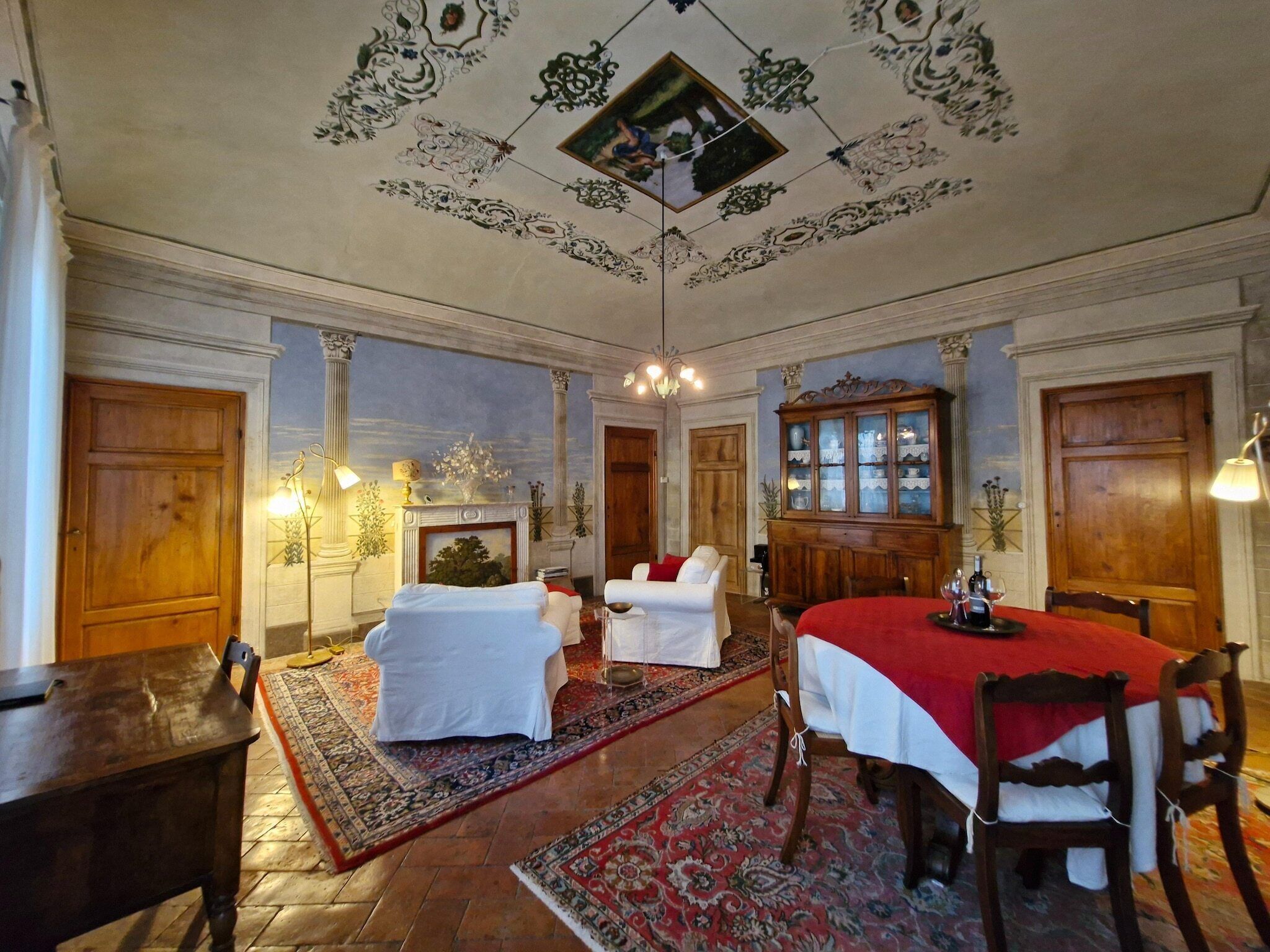Una habitación amplia con una gran mesa de comedor, una chimenea y un candelabro.