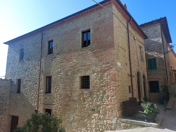 A stone building with multiple windows and a bench outside.