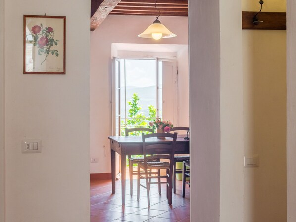 A dining area with a table and chairs, a hanging light fixture, and a framed botanical print on the wall.