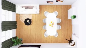 A room with a wooden floor, a white sofa, a dining table with six chairs, a small round table with a black table runner, and a potted plant. - 4-room residence for families and groups with balcony and garden view! (Leipzig)