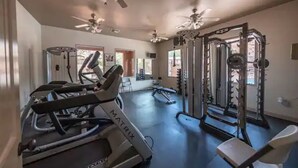 Een fitnessruimte met loopbanden, krachtapparaten en plafondventilatoren.