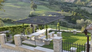 Un patio con pavimento in pietra, una pergola e panche in pietra.