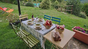 An outdoor dining setup with a table set for two, surrounded by chairs, with a scenic mountain view in the background.
