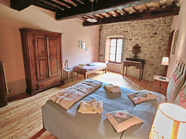 Un dormitorio acogedor con una cama grande, un armario de madera, una pared de piedra y una ventana que proporciona luz natural.