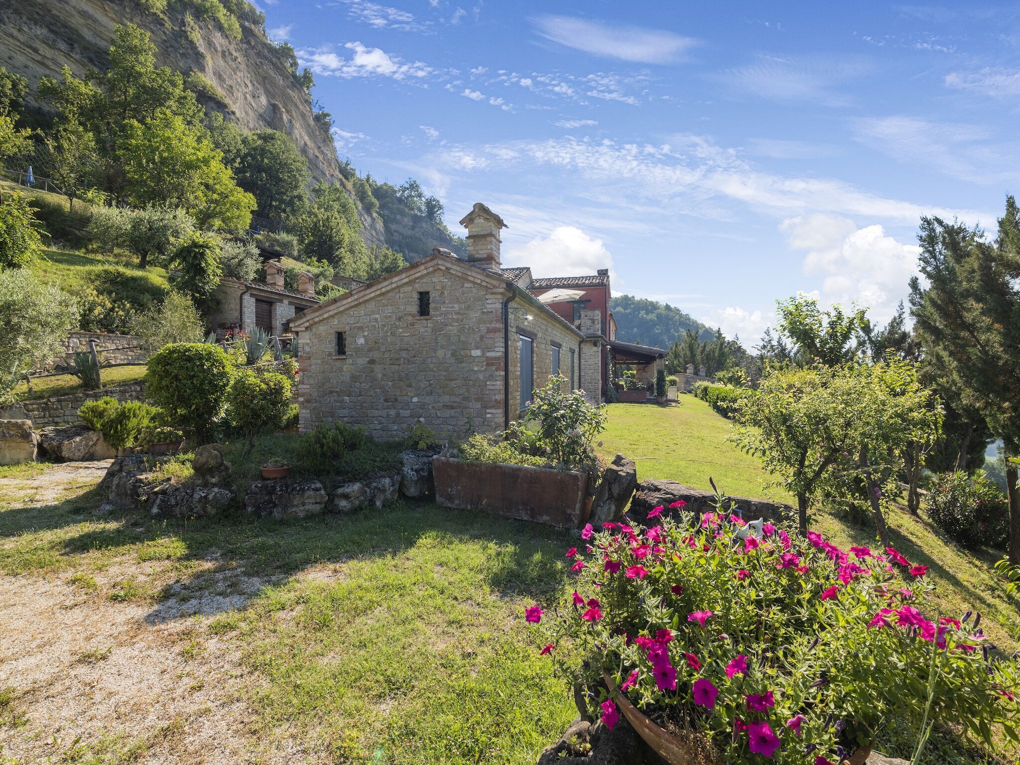 A stone house with a small garden and a view of a mountain.