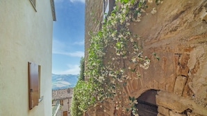 A narrow alleyway with a stone wall on one side and a white building on the other. - Relaxing Retreat with bike access (Monte san Martino)