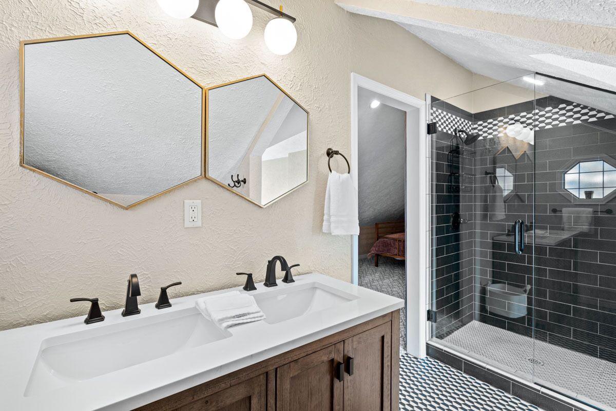 Une salle de bain avec deux lavabos, un miroir et un espace douche.