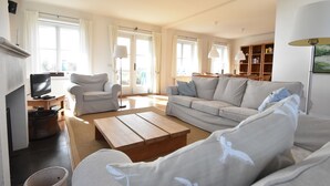 A spacious living room with a sofa, armchairs, and a television. - Villa in Midsland near the Sea (Midsland Terschelling)