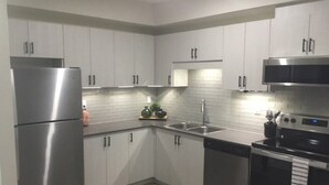 A modern kitchen with stainless steel appliances, white cabinetry, and a built-in oven.
