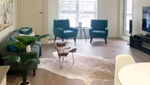 A modern living room with a sofa, two armchairs, a coffee table, and a TV.