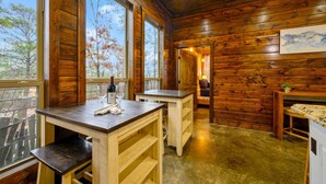 Interno rustico di una baita di legno con ampie finestre, un tavolo in legno e una panca.