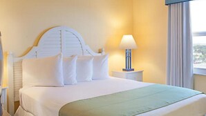 Una habitación de hotel con una cama, una mesita de noche con lámpara y una ventana con cortinas.