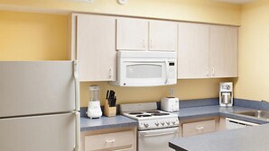 Una cocina con refrigerador, microondas, estufa y lavaplatos.