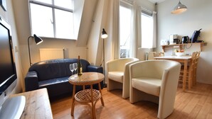 Un salon moderne comprenant un canapé, des fauteuils, une petite table et un coin repas.