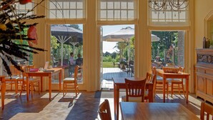 Un comedor amplio con ventanas grandes, muebles de madera y un candelabro.