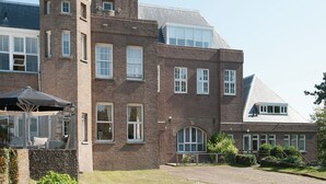 A large brick building with a prominent tower and multiple windows. - Apartment in Bergen aan Zee near the Beach (Bergen aan Zee)