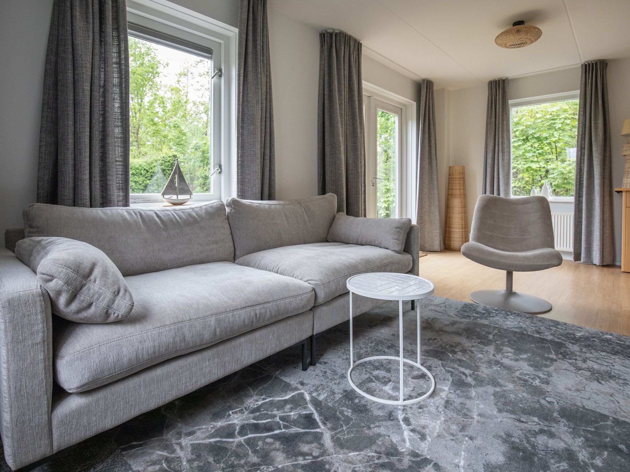 A modern living room with a grey sofa, a small round table, and a chair.