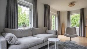 A modern living room with a grey sofa, a small round table, and a chair. - Holiday home near Grevelingen Lake (Zonnemaire)
