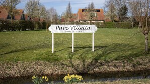 A sign for "Parc Villette" with a grassy area and a small body of water in the foreground. - Holiday home near Grevelingen Lake (Zonnemaire)