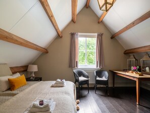 A cozy attic bedroom with a bed, two chairs, a desk, and a window with curtains. - Mansion in Deil by River Linge (Deil)