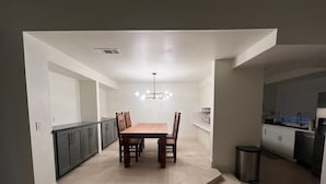 Uma cozinha moderna com área de jantar, com ilha central, armários cinza e lustre.
