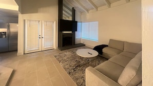 Uma sala de estar com lareira, sofá, mesa de centro e televisão.