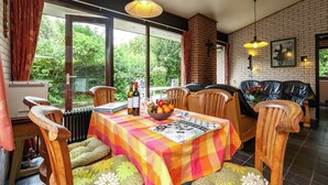 A dining area with a table set for two, a brick fireplace, and a view of greenery outside. - Lake Escape w/ Garden (Kamperland)