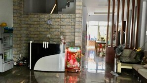 A modern living room with a stone wall, a black and white sofa, a dining area, and a staircase. - Manh Long Hotel Q2 - by Bay Luxury (Ho Chi Minh City)