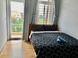 Un dormitorio con cama, ventana con cortinas y vistas a un balcón.