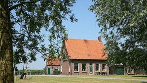 A traditional brick building with a tiled roof, a green door, and a small attached structure. - Pet-Friendly Farmhouse (Eede)