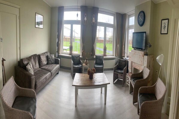 A living room with a sofa, chairs, a coffee table, a television, and a fireplace.