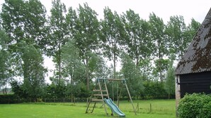 A grassy area with a wooden swing set and a slide. - Pet-Friendly Farmhouse (Eede)