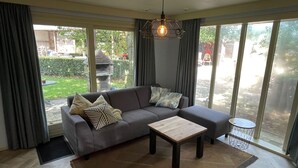 A modern living room with a grey sectional sofa, a wooden coffee table, and a large window with curtains.