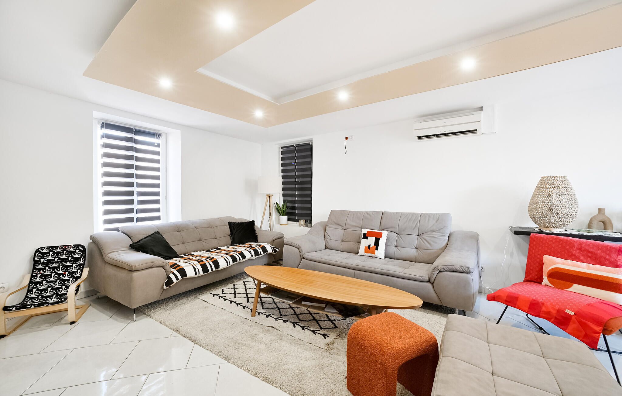 A modern living room with a sofa, coffee table, and a red chair.
