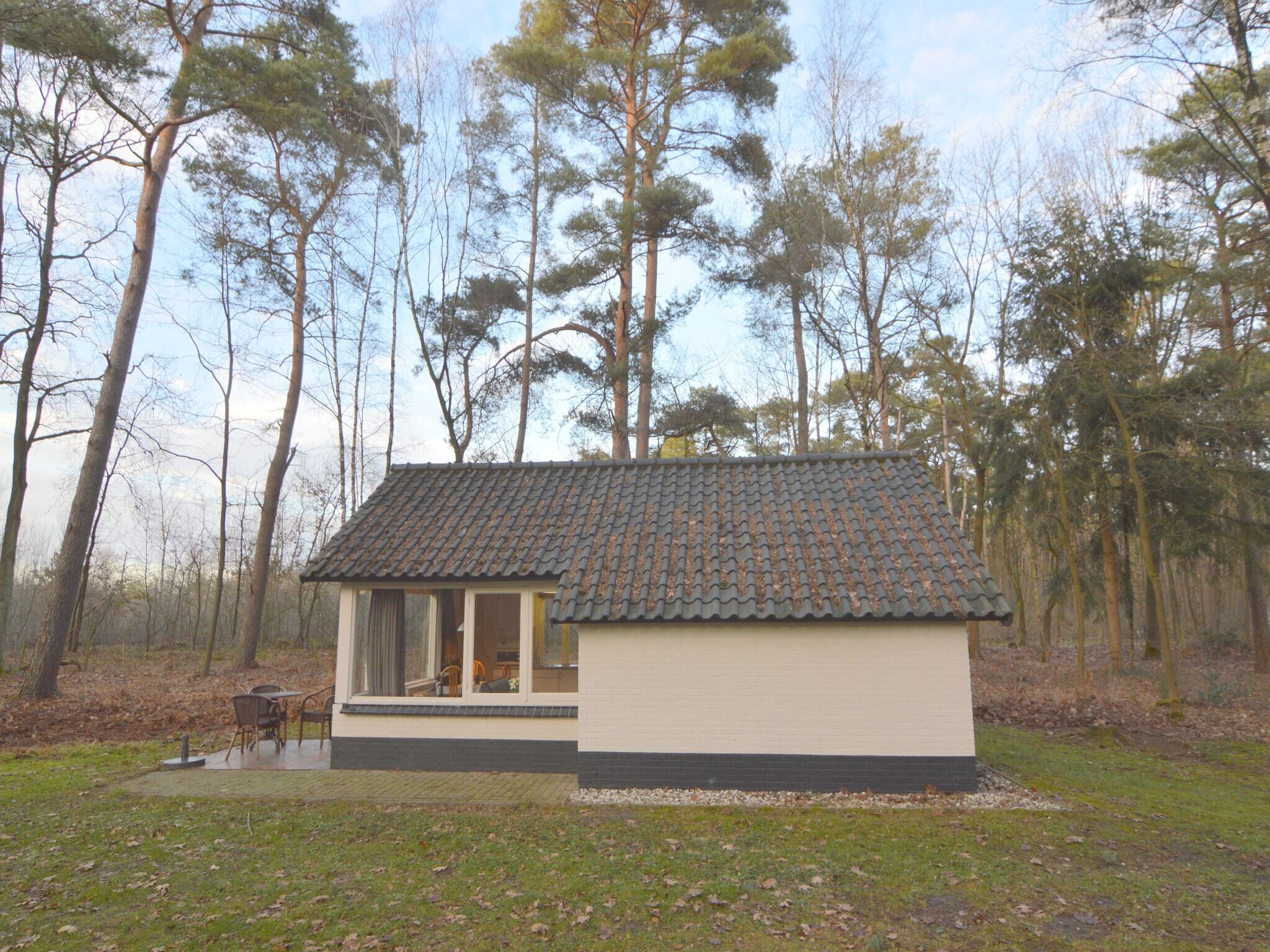 Ett litet hus i en våning med ett tak täckt av tegelpannor, beläget i ett skogsområde.