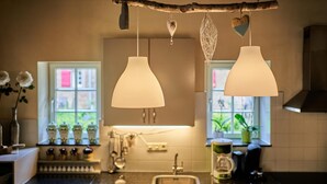 A kitchen with two pendant lights, a window with a view, and a coffee maker on the counter. - Group Retreat in Mesch (Mesch-Eijsden)