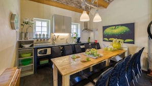 A kitchen with a wooden table, chairs, and a dining area. There are cabinets, a microwave, and a window. - Group Retreat in Mesch (Mesch-Eijsden)